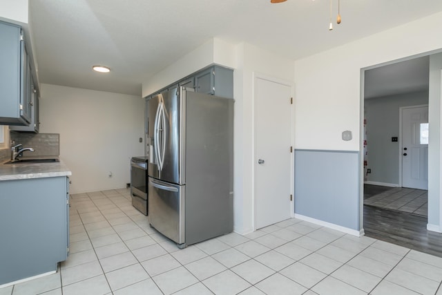 kitchen featuring light tile patterned flooring, sink, appliances with stainless steel finishes, gray cabinets, and decorative backsplash