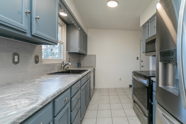 kitchen with light tile patterned flooring, appliances with stainless steel finishes, sink, and tasteful backsplash