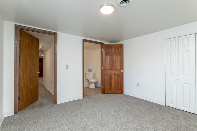 unfurnished bedroom featuring light carpet, connected bathroom, and a closet