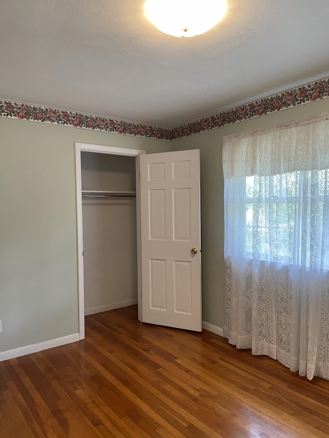 unfurnished bedroom with hardwood / wood-style flooring and a closet