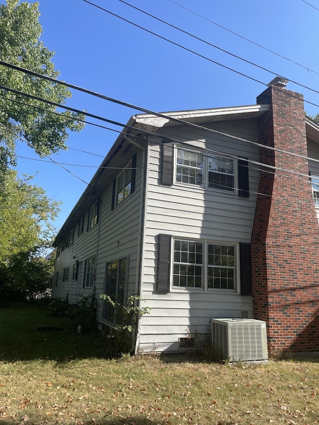 view of side of home with central AC and a lawn