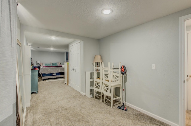 hallway with light colored carpet and a textured ceiling