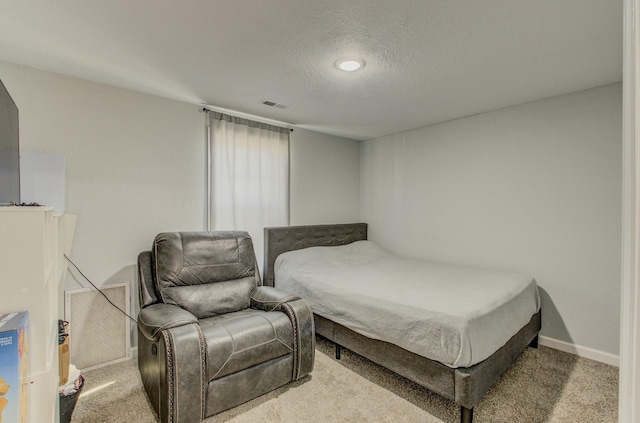 bedroom with light colored carpet and a textured ceiling