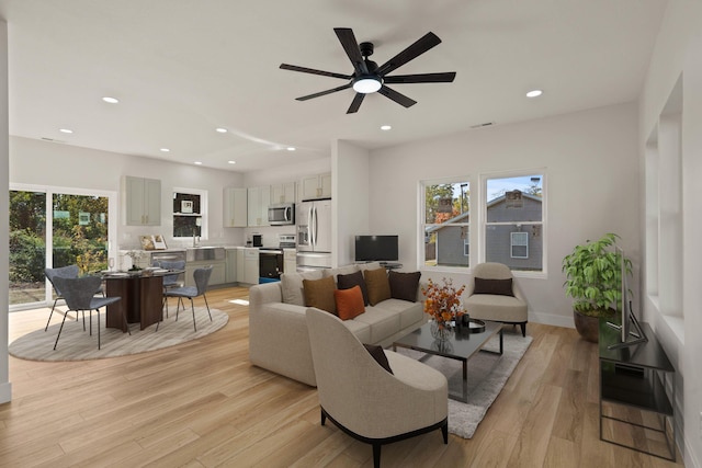 living room featuring ceiling fan, a healthy amount of sunlight, sink, and light hardwood / wood-style floors