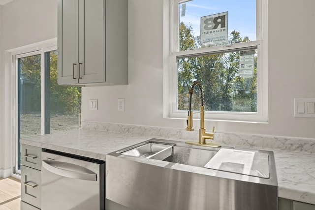 kitchen with light stone counters, sink, gray cabinets, and stainless steel dishwasher