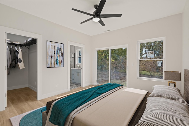 bedroom with ceiling fan, ensuite bathroom, light hardwood / wood-style floors, a spacious closet, and a closet