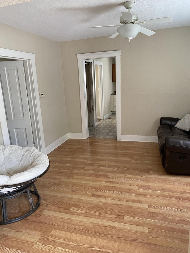 sitting room with ceiling fan, a textured ceiling, and light wood-type flooring