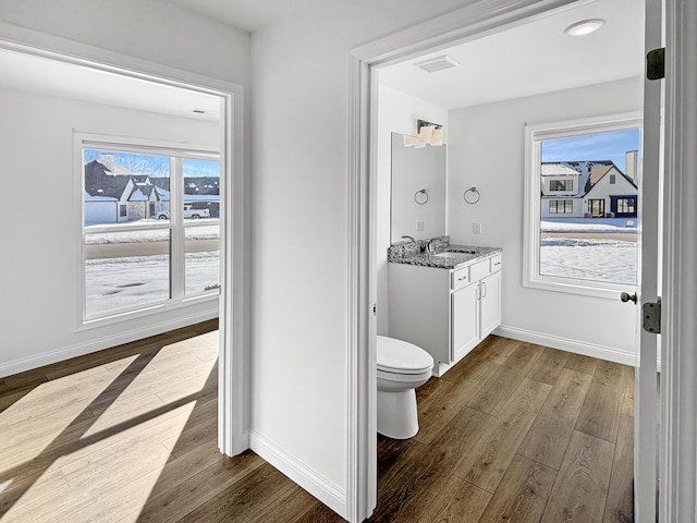 bathroom featuring vanity, toilet, hardwood / wood-style floors, and a wealth of natural light