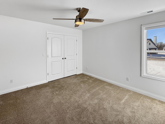 unfurnished bedroom with a textured ceiling, a closet, ceiling fan, and carpet