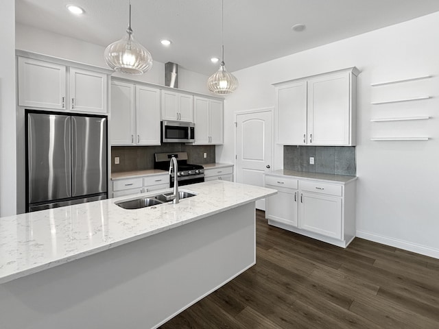 kitchen with sink, white cabinetry, appliances with stainless steel finishes, pendant lighting, and light stone countertops