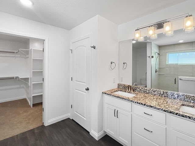 bathroom with hardwood / wood-style flooring, vanity, toilet, and walk in shower