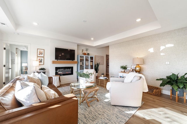 living room with light hardwood / wood-style floors and a tray ceiling