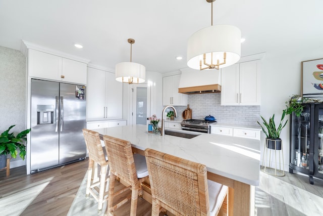 kitchen with stainless steel appliances, hanging light fixtures, sink, and white cabinets