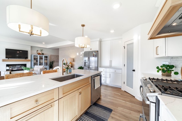 kitchen with pendant lighting, sink, premium range hood, appliances with stainless steel finishes, and light brown cabinetry