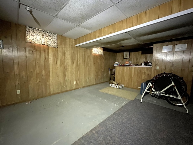 basement with a drop ceiling and wood walls