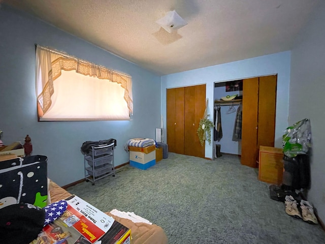 bedroom with multiple closets, carpet, and a textured ceiling