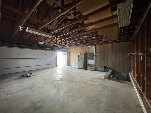 garage with black refrigerator, a garage door opener, and wood walls