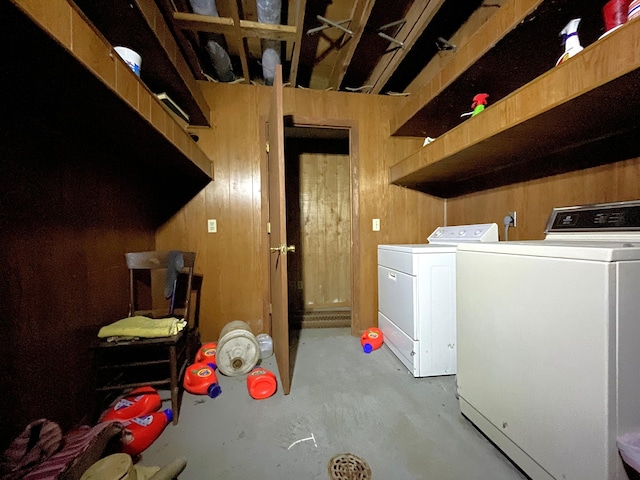 laundry room with washing machine and dryer and wood walls