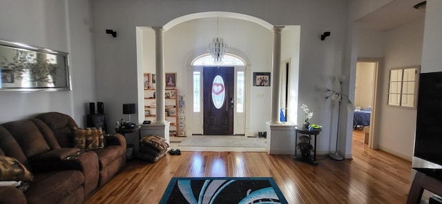 foyer featuring hardwood / wood-style flooring, decorative columns, and a towering ceiling