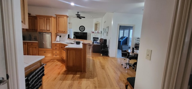 kitchen with a kitchen island, sink, ceiling fan, kitchen peninsula, and light hardwood / wood-style flooring