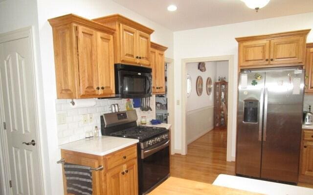 kitchen with stainless steel appliances, decorative backsplash, and light hardwood / wood-style flooring