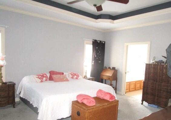 bedroom featuring ensuite bathroom, crown molding, light colored carpet, a tray ceiling, and ceiling fan