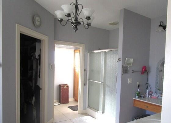 bathroom with an enclosed shower, tile patterned flooring, and an inviting chandelier