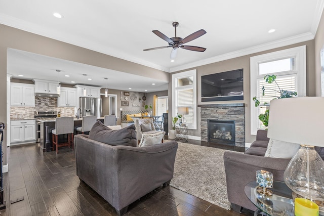 living room with crown molding, ceiling fan, a fireplace, and dark hardwood / wood-style flooring