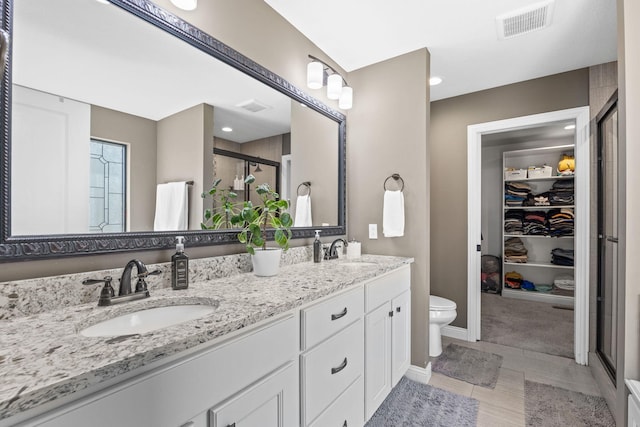 bathroom with a shower with door, vanity, tile patterned floors, and toilet