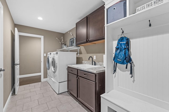 laundry area featuring sink, light tile patterned floors, washer and clothes dryer, and cabinets