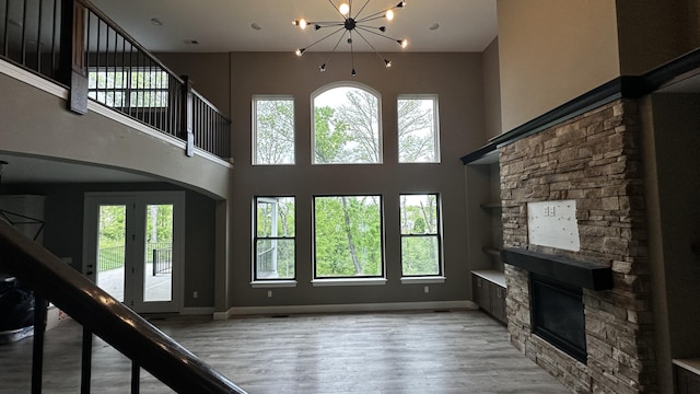 7333 Sella Ct, Columbia, MO 65203 - unfurnished living room featuring a fireplace, plenty of natural light, a chandelier, wood finished floors, and a high ceiling