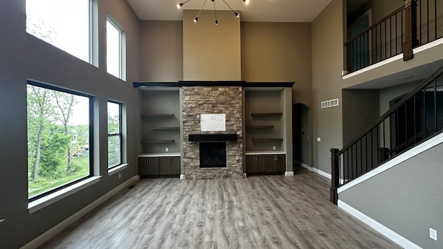 7333 Sella Ct, Columbia, MO 65203 - unfurnished living room featuring a high ceiling, baseboards, wood finished floors, stairway, and a stone fireplace