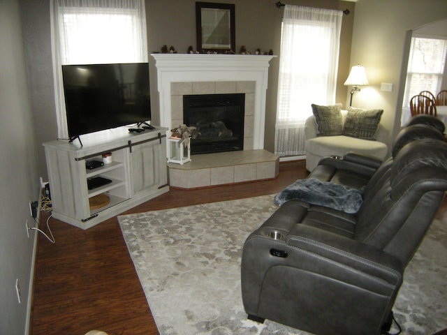 living room with a tiled fireplace and dark wood-type flooring