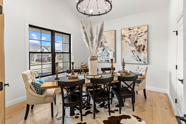 dining room featuring high vaulted ceiling, light hardwood / wood-style floors, and a notable chandelier