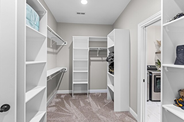 spacious closet with light colored carpet and washing machine and dryer