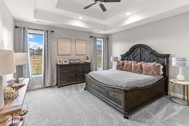 bedroom with a raised ceiling, crown molding, light carpet, and ceiling fan