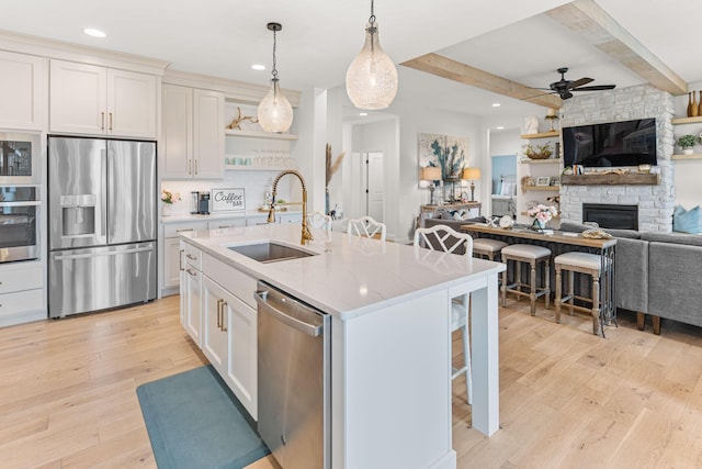 kitchen with stainless steel appliances, sink, a breakfast bar area, and white cabinets