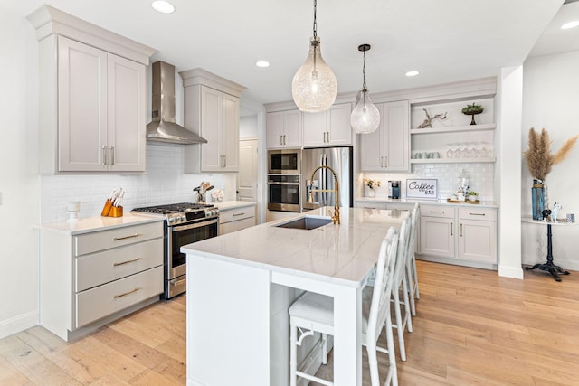 kitchen with pendant lighting, a kitchen island with sink, stainless steel appliances, a kitchen breakfast bar, and wall chimney exhaust hood