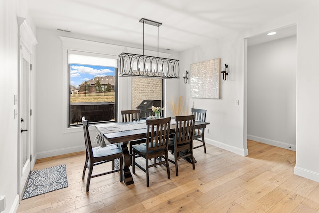 dining room with light hardwood / wood-style flooring and a chandelier