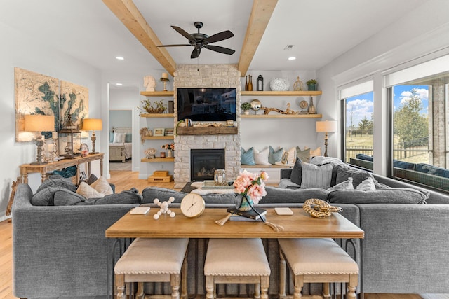 living room with ceiling fan, a fireplace, beam ceiling, and light hardwood / wood-style flooring