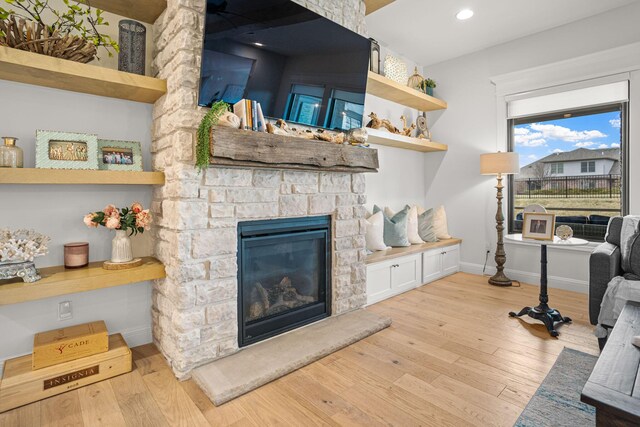 living room with a stone fireplace and light hardwood / wood-style floors