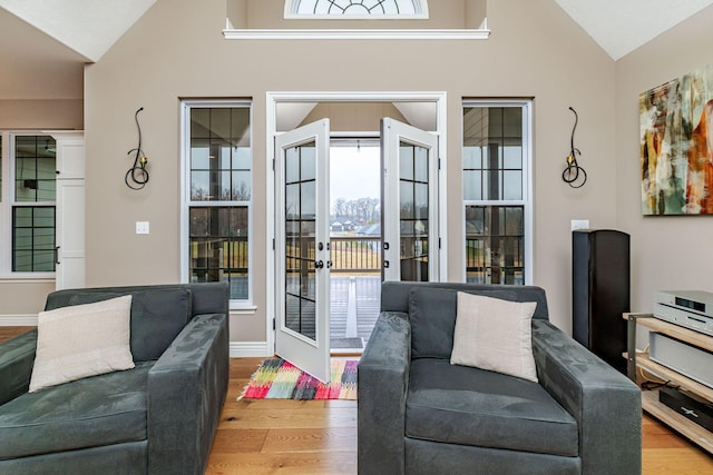 living room with lofted ceiling, light hardwood / wood-style floors, and french doors