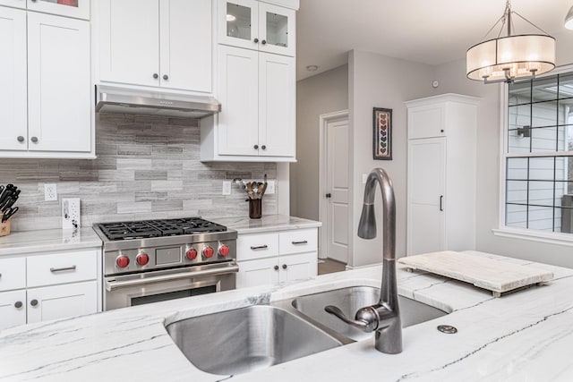 kitchen featuring pendant lighting, light stone countertops, white cabinetry, and high end stove