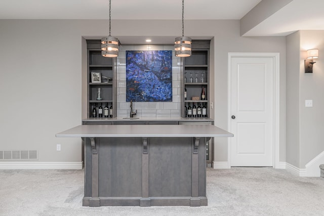 bar featuring pendant lighting, sink, tasteful backsplash, and light colored carpet