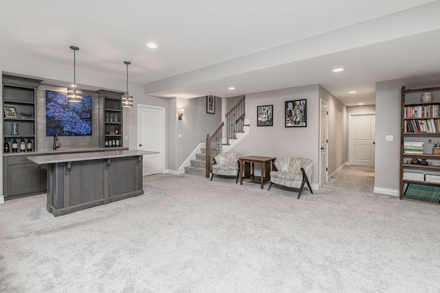 interior space featuring light carpet, hanging light fixtures, gray cabinets, and sink