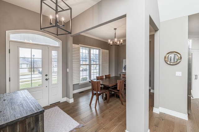 entryway featuring ornamental molding, hardwood / wood-style floors, and a notable chandelier