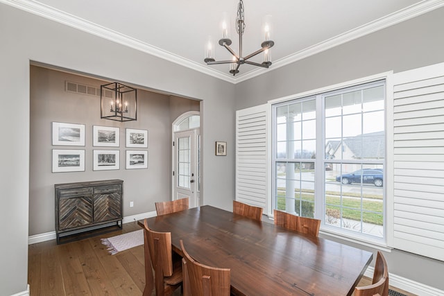 dining space featuring an inviting chandelier, ornamental molding, and dark wood-type flooring