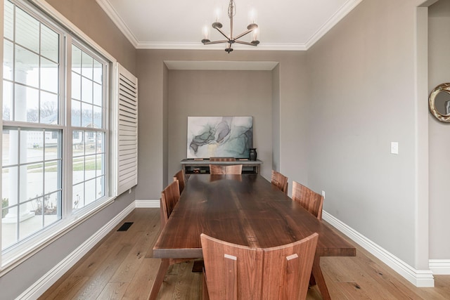 dining room with ornamental molding, a chandelier, and light hardwood / wood-style floors