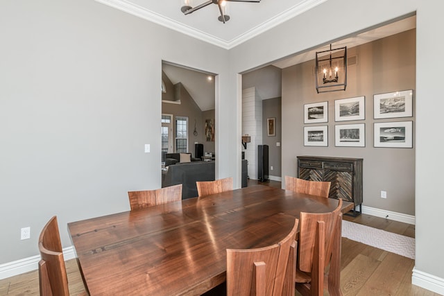 dining area with crown molding, vaulted ceiling, hardwood / wood-style floors, and an inviting chandelier