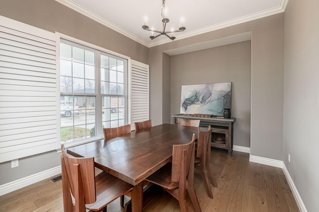 dining area with crown molding, hardwood / wood-style floors, and a chandelier